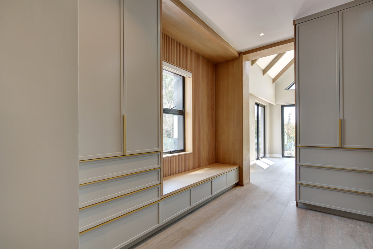 Modern interior with light-colored walls, wooden bench, and large windows.