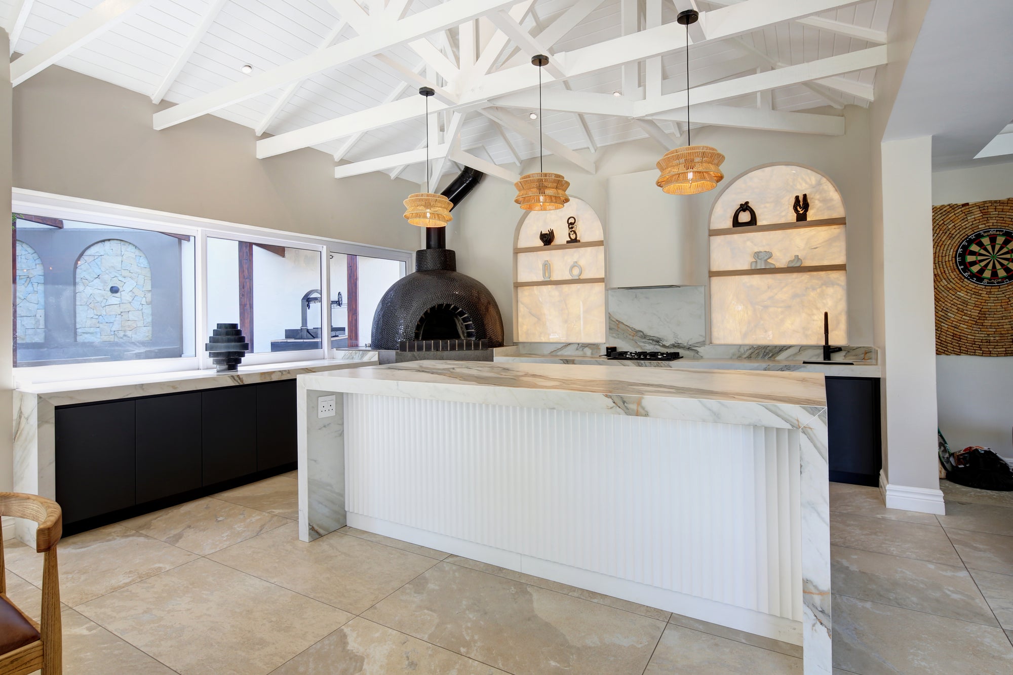 Modern kitchen with white island, stone countertops, and exposed beams.
pizza Oven